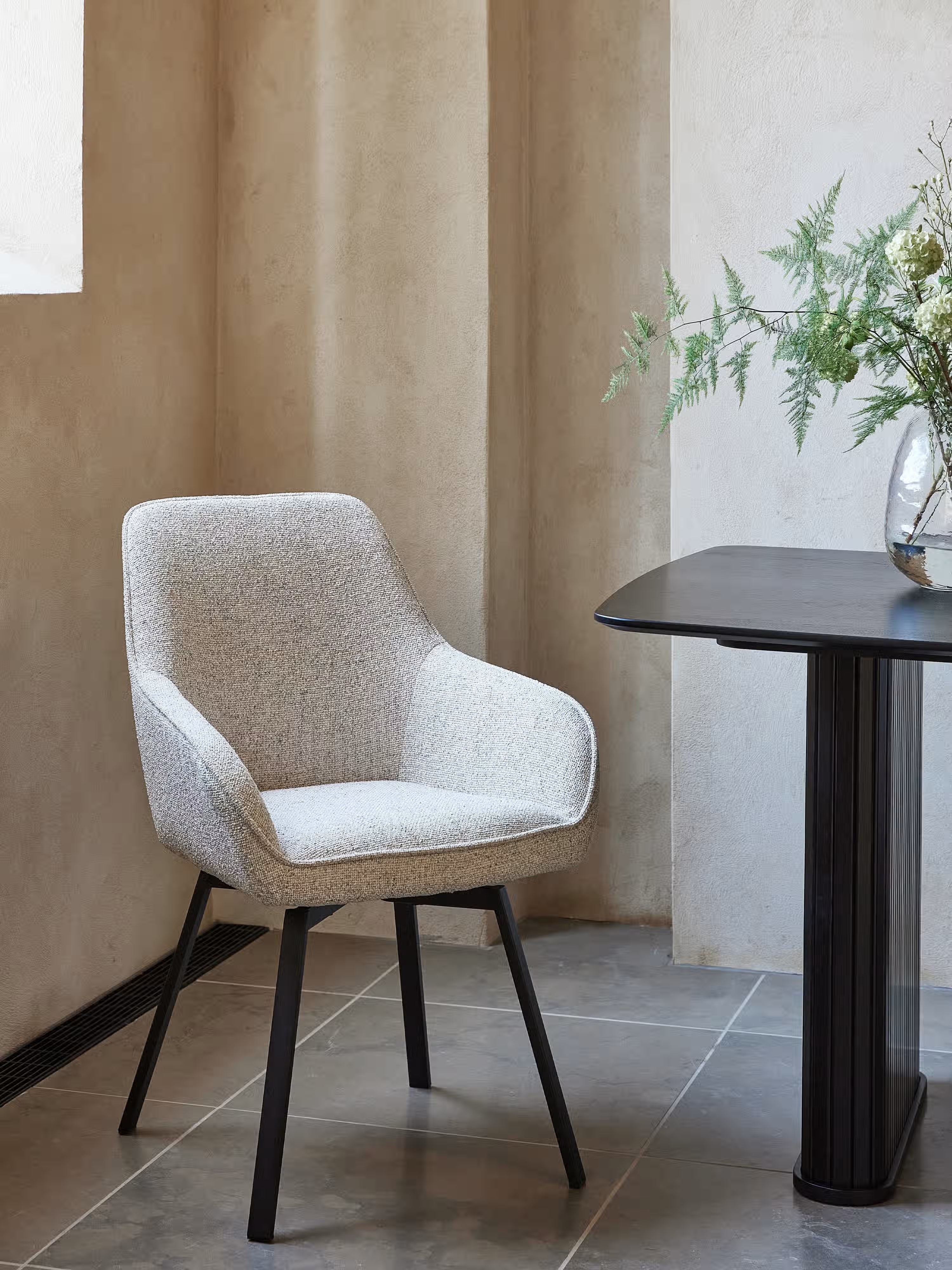 Alma swivel padded chair in melange bouclé fabric with black metal base
