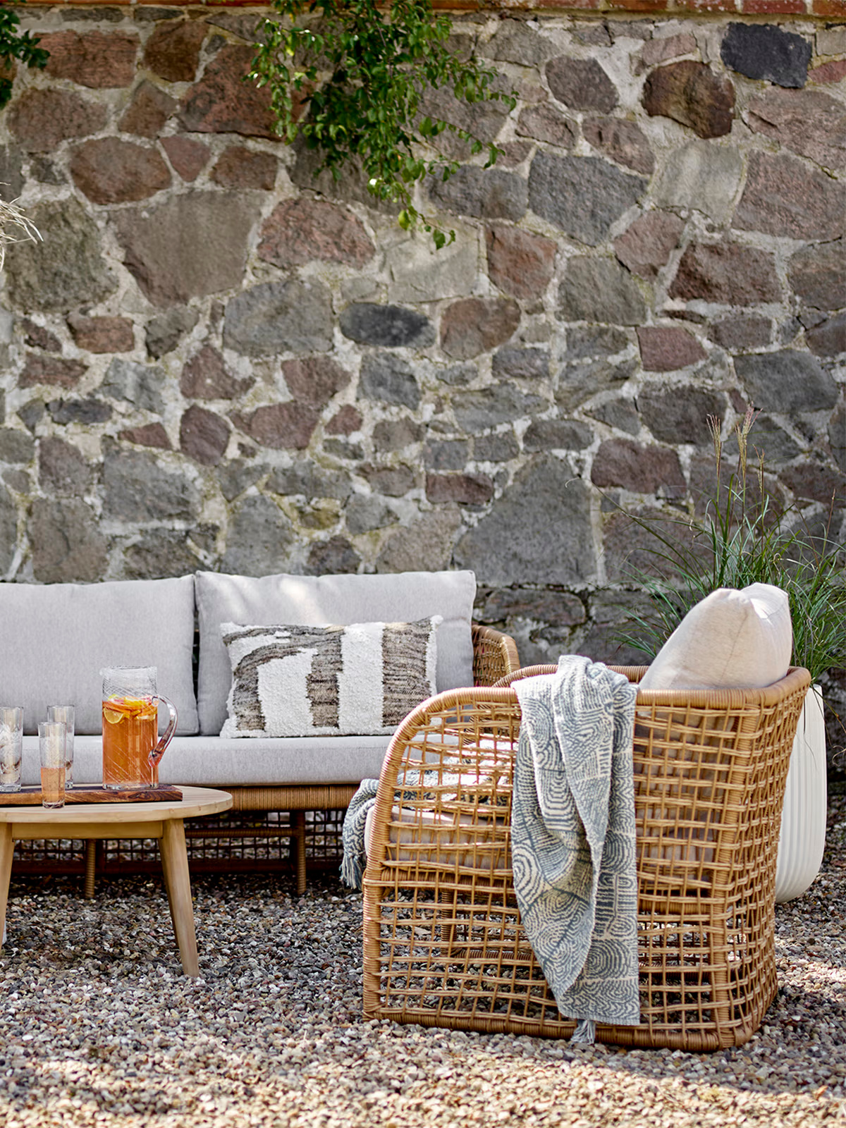Penzano Sessel für den Außenbereich aus synthetischem Rattan in Naturfarbe mit Kissen